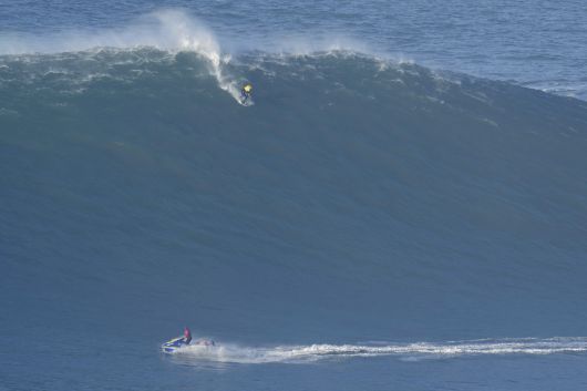 서퍼가 파도를 타고 내려오는 모습을 제트 스키어가 바라보고 있다. 서프가 위험에 처하면 즉시 구조에 착수한다. AP=연합뉴스