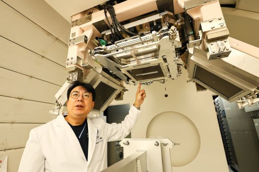이익재 연세의료원 중입자치료센터장이 회전형 치료기에서 중입자 빔이 나오는 곳을 가리키고 있다. 좌우 사선으로 걸려 있는 패널은 암의 위치를 파악할 수 있는 X선 장비다.