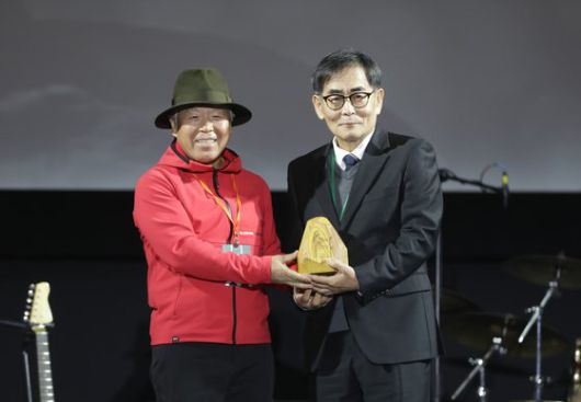 전날(20일) 울산 울주군 영남알프스 복합웰컴센터에서 열린 '제8회 울산울주세계산악영화제' 개막식에서 특별 공로상으로 선정된 산악인 김영도 고문(99세)을 대신해 아들이 무대에 올라 대리 수상을 하고 엄홍길 집행위원장과 기념촬영을 하고 있다. 뉴스1