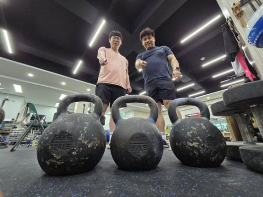 안산 선부중 역도부 조성현(50·왼쪽) 코치와 안산공고 역도부 박상민(32) 코치가 역도 여자 81㎏ 이상급 국가대표 박혜정(21·고양시청)이 월등한 기량을 보여 새로 들였다는 케틀벨을 가리키고 있다. 손성배 기자