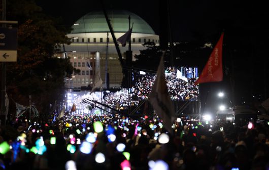윤석열 대통령 탄핵소추안이 가결된 지난해 12월 14일 서울 여의도 국회 앞에서 열린 촛불집회에 참석한 시민들이 응원봉과 촛불을 켠 채 환호하고 있다. 연합뉴스