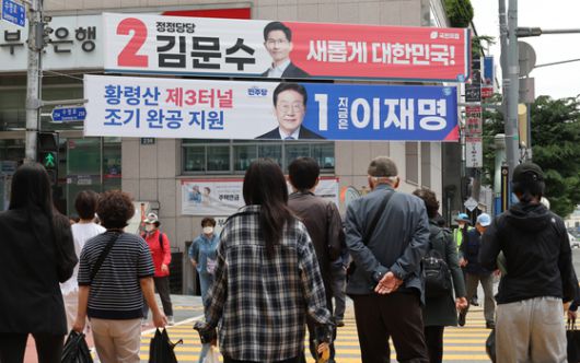 제21대 대통령 선거를 앞두고 19일 부산 남구 한 도로변에서 유권자들이 각 당의 대선 후보자를 알리는 현수막을 살펴보고 있다. 송봉근 기자