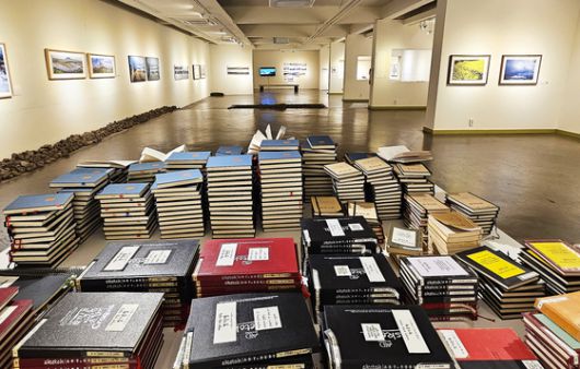 김영갑 20주기 전시회가 진행 중인 김영갑갤러리 두모악. 사진 아래에 쌓아놓은 노트가 2003년 갤러리를 열었을 때부터 모은 방명록이다.