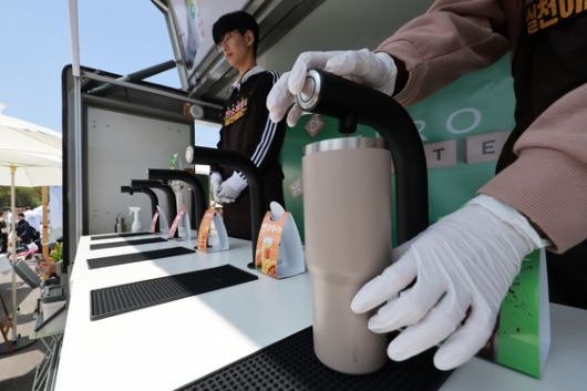 서울 영등포구 여의도공원에서 열린 2025 지구의 날 기념행사에서 부스 관계자가 텀블러를 가져온 시민에게 음료를 따라주고 있다. [연합뉴스]