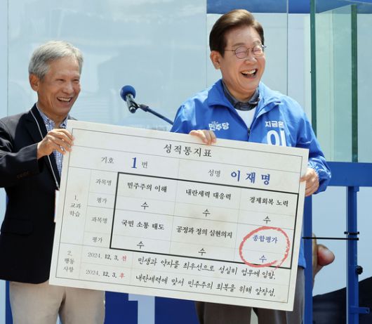 제21대 대선을 이틀 앞둔 지난 1일 고향인 경북 안동 등 영남 지역을 찾은 이재명 더불어민주당 대선후보가 안동시 웅부공원 유세에서 초등학교 은사인 박병기씨로부터 ‘후보 성적통지표’를 받고 활짝 웃고 있다. 김성룡 기자