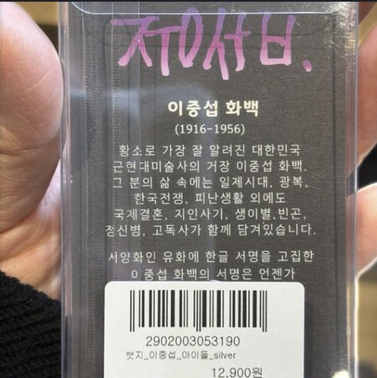 '아이들' 뱃지의 뒷면. 고(故) 이중섭 화백에 관한 설명이 100자 넘게 적혀 있다. 이 화백의 유족은 이런 점 등을 토대로 해당 뱃지의 제작자가 소비자를 적극적으로 속이려 해 사기죄에 해당한다고 주장한다. 고(故) 이중섭 화백의 조카 손녀 이지연씨