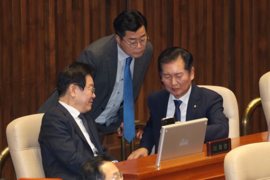지난해 9월 11일 당시 더불어민주당 이재명 대표와 박찬대 원내대표(가운데), 정청래 의원(오른쪽)이 대정부 질문이 진행된 국회 본회의장에서 휴대전화를 함께 보며 대화하고 있다. 연합뉴스