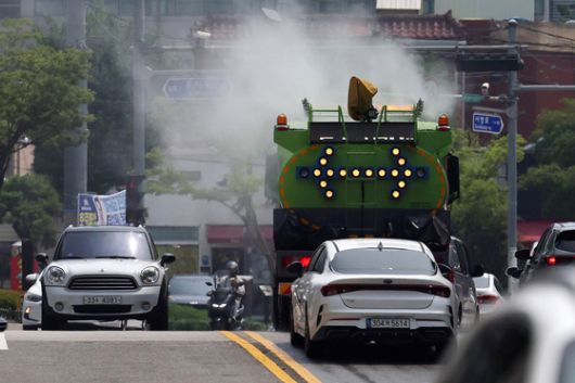 낮 기온이 30도를 웃돌아 무더운 날씨를 보인 26일 광주 북구청 기후환경과 직원들이 살수차를 이용해 도로의 지열을 식히고 있다. 광주 북구 제공