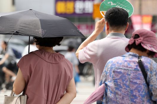 폭염이 일주일 넘게 이어진 4일 오후 대구 수성구 달구벌대로에서 시민들이 양산과 부채로 뙤약볕을 가리고 있다. 뉴스1