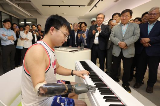 양손을 잃고 브레인코의 스마트 인공 손을 착용한 남성이 한비청 CEO 옆에서 붓글씨를 쓰고 있다. 장진영 기자