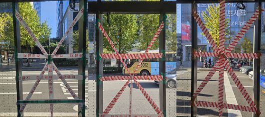 지난 2023년 12월 6일 오후 50대 남성이 홍대입구 버스정류장에서 넘어지며 머리를 다쳐 2주 간 치료를 받다 숨지는 사고가 발생했다. 사진은 시설관리업체가 2023년 11월 8일 디지털 광고 패널을 철거한 뒤 테이프를 붙여 놓은 빈 공간 3곳을 이어 붙여 편집했다. 사진 독자 제공