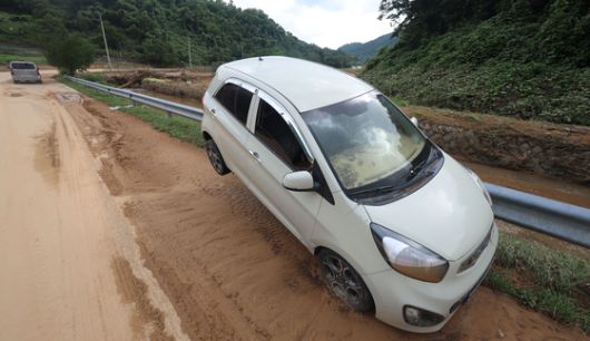 21일 오후 경남 산청군 생비량면 한 하천 옆 가드레일에 집중호우 피해자의 것으로 추정되는 경차가 걸쳐져 있다. 연합뉴스