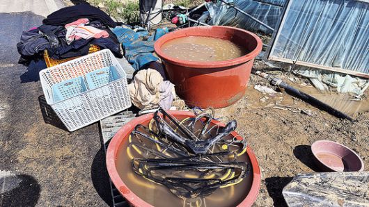 지난 21일 경남 산청군 신안면의 한 식당에서 식당 관계자가 컵라면을 먹기 위해 도구를 챙기고 있다.   식당 관계자는 "호우 여파로 단전, 단수, 가스 공급이 중단됐고, 선풍기 돌릴 전기를 위층에서 끌어다가 쓰는 중이다"고 설명했다. 연합뉴스