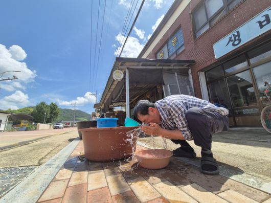 지난 21일 경남 산청군 신안면의 한 식당에서 식당 관계자가 공급받은 물로 흙탕물이 묻은 창문을 씻고 있다.   식당 관계자는 "호우 여파로 단전, 단수, 가스 공급이 중단됐고, 선풍기 돌릴 전기를 위층에서 끌어다가 쓰는 중이다"고 설명했다. 연합뉴스
