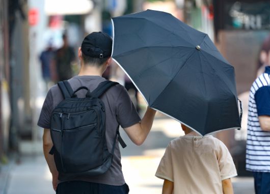 전국 대부분 지역에 폭염 특보가 이어진 지난 9일 대구 중구 동성로에서 한 시민이 자녀에게 양산을 씌워주며 이동하고 있다. 뉴스1