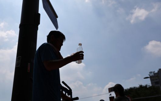 폭염이 이어지고 있는 28일 서울 동대문종합시장 인근에서 한 근로자가 원단을 옮긴 후 물을 마시며 휴식을 취하고 있다. 연합뉴스