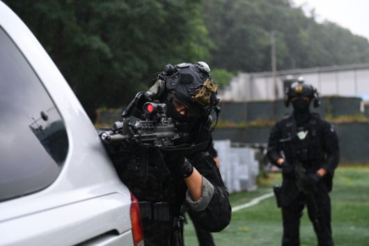 차량 근접전술 사격(VCQB) 훈련에서 차량에 몸을 숨겨 사격하고 있는 공군 장병. 육군 장병이 뒤에서 이를 지켜보고 있다. 공군 17전비