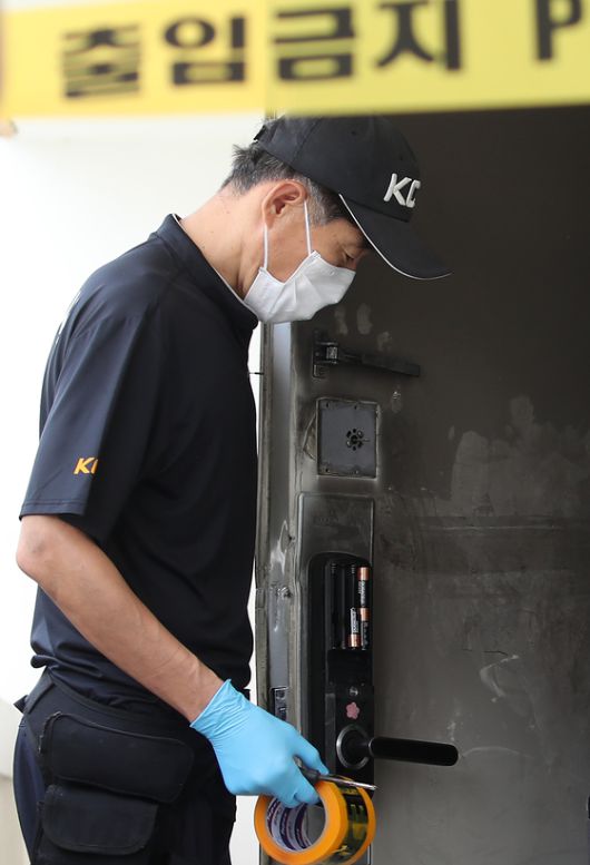 지난 10일 오후 경찰이 아파트 주변을 통제한 뒤 현장감식을 진행하고 있다. 불이 난 아파트 현관 출입문 잠금장치(도어락)에 건전지 일부가 빠져 있다. 뉴스1