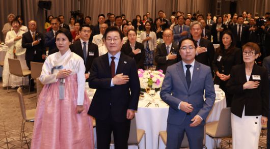 이재명 대통령과 김혜경 여사가 24일(현지시간) 미국 워싱턴DC의 한 호텔에서 열린 동포 만찬 간담회에서 국기에 경례하고 있다. 이 대통령 오른쪽은 앤디 김 미국 상원의원. 연합뉴스