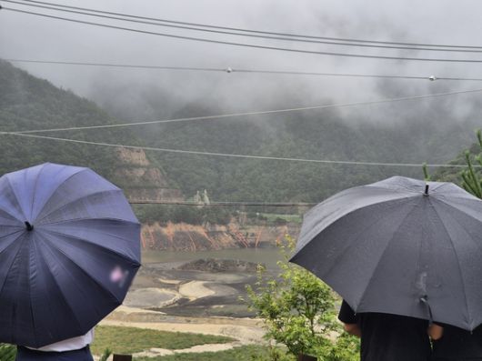 극심한 가뭄을 겪고 있는 강원 강릉지역에 많은 비가 내린 지난 13일 오전 우산을 쓴 시민이 마른 저수지에 내리는 단비를 바라보고 있다. [뉴스1]