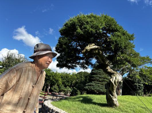 성범영 생각하는 정원 원장이 지난 8월 25일 예전에 작업을 하다 떨어진 나무 앞에서 미소를 짓고 있다. 최충일 기자