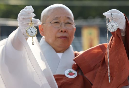 진관사 주지 법해스님이 25일 김진 광복회 부회장에게 받은 김구 선생과 윤봉길 의사가 교환했던 회중시계 복각을 들어보이고 있다. 김경록 기자