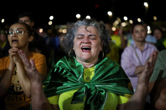Supporters of Brazil's former President Jair Bolsonaro pray as they attend a vigil following Bolsonaro's detention by Federal Police, ending months of house arrest, in Brasilia, Brazil, November 22, 2025. REUTERS/Mateus Bonomi