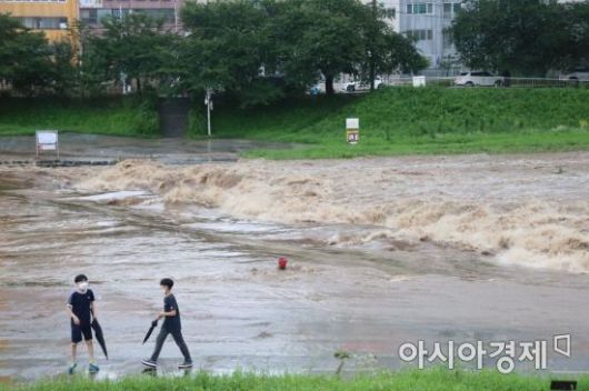 지난 28일부터 내린 장맛비가 29일 오후까지 이어지고 있는 가운데 학생 두 명이 불어난 광주천 산책로를 위태롭게 걷고 있다.