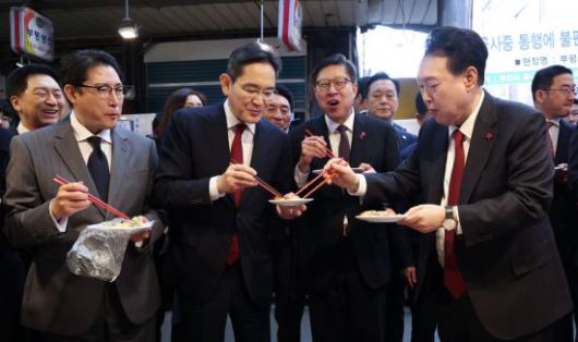 윤석열 대통령이 6일 부산 중구 깡통시장에서 재계 총수들과 분식을 맛보며 이재용 삼성전자 회장, 조현준 효성그룹 회장에게 빈대떡을 나눠주고 있다. [이미지출처=연합뉴스]