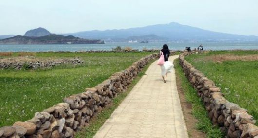 돌담길을 따라 가파도를 산책하고 있는 여행객