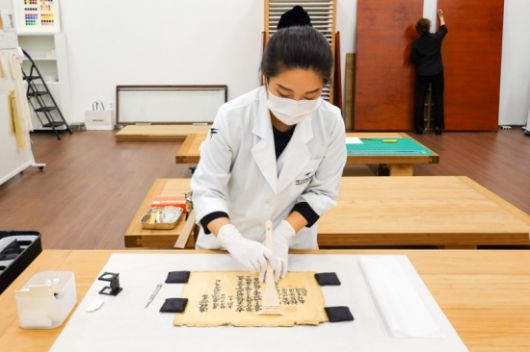 대구간송미술관 수리복원 전문 학예사가 ‘희원학교 진급증서’의 건식 클리닝을 진행하고 있다. 대구간송미술관