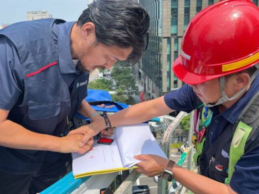 김형수 거제통영고성조선하청지회장(왼쪽)이 서울 여의도 한화 본사 앞 고공 농성장에서 장창열 금속노조 위원장과 함께 한화오션 하청 노사 간 합의서에 도장을 찍고 있다. 금속노조 경남지부 제공
