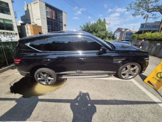 23일 낮 12시 10분께 광주 서구 쌍촌동 한 아파트 지상 주차장에서 땅 꺼짐(싱크홀)이 발생, 주차 중이던 스포츠유틸리티차(SUV) 뒷바퀴가 빠져 있다. 서구청 제공