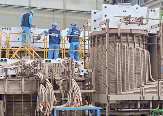 부산 강서구 LS일렉트릭 부산사업장에서 작업자가 초고압변압기를 생산하고 있다. 전선을 코일처럼 감아 만든 권선을 감싸고 있는 갈색 소재는 목재 펄프로, 유입변압기의 절연성을 담보하는 핵심 재료다. LS일렉트릭