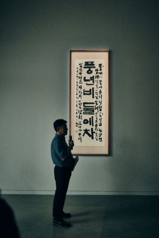 30여년간 평보 서희환의 작품을 수집하고 연구해온 고창진 수집가가 자신의 수집품 앞에서 설명하고 있다. 해당 작품은 '풍년비'와 '들에차'가 분리된 것을 고창진 수집가가 수소문 끝에 '풍년비' 부분을 찾아 완성본으로 만들었다. 예술의전당 서울서예박물관