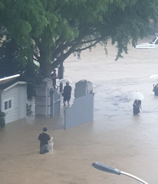 무릎 높이까지 찬 물속을 걸어 나오는 시민들. 18일 오후 광주의 한 주택가 일대가 폭우로 잠기면서 주민들이 우산을 들고 물을 헤치며 이동하고 있다. 엑스 갈무리