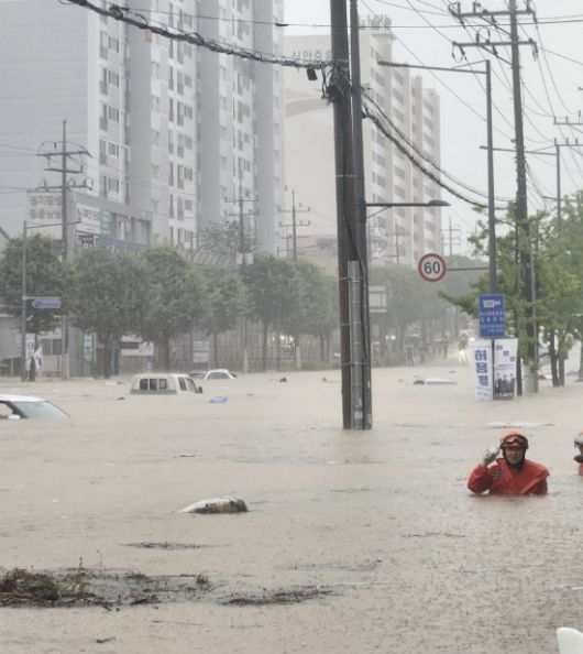 차량들만 둥둥 떠다닌다. 18일 오후 광주 북구 신안동 한 도로가 폭우로 완전히 잠겨 구조대원이 허리까지 찬 물을 헤치며 수색에 나서고 있다. 엑스 갈무리