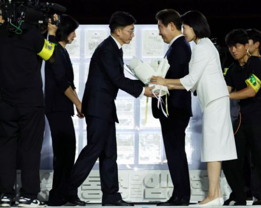 이재명 대통령과 김혜경 여사가 15일 서울 세종대로 광화문광장에서 열린 제21대 대통령 국민임명식 '광복 80년, 국민주권으로 미래를 세우다' 행사에서 국민 대표인 이국종 국군대전병원장으로부터 '빛의 임명장'을 받고 있다. 연합뉴스