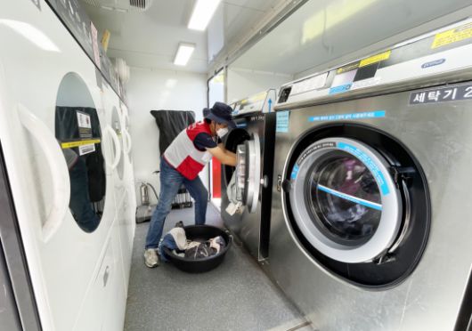 희망브리지 자원봉사자가 이동식 세탁구호차량 내부에서 수거한 세탁물을 세탁하고 있다. 희망브리지