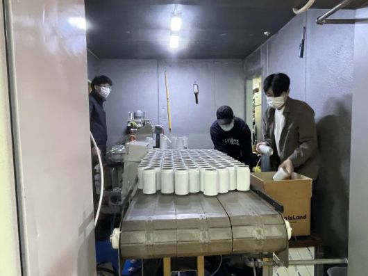 직원들이 컨베이너 벨트에서 가공된 맥주 캔을 담고 있다.