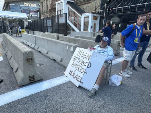 공화당 전당대회가 열리는 파이서브 포럼(Fiserv Forum) 경기장에 들어가는 입구에 베키 매닝스 씨가 패널을 들고 1인 시위를 하고 있다. (사진=김상윤 특파원)