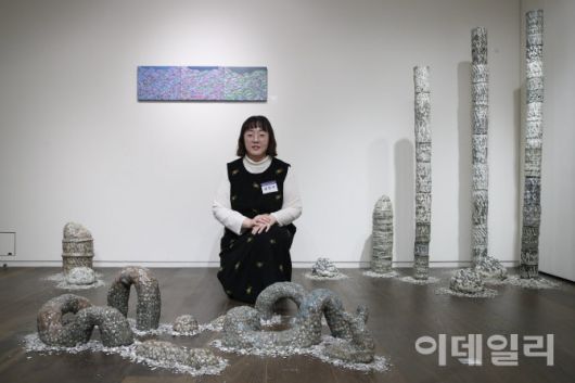 곽재선문화재단 ‘제3회 아트공모전’에서 대상을 수상한 작가 김민지가 수상작 ‘탈피’(2022, 120×70×45㎝) 뒤에 앉았다. 작가 뒤 오른쪽으로 조각작품 ‘성장통’(2021∼2022, 11×11×160∼200㎝)이, 왼쪽으로 부조작품 ‘줄기’(2024, 27×35㎝ 3점)가 보인다(사진=이영훈 기자).