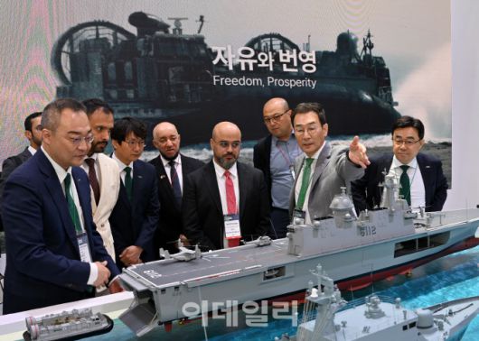 HJ중공업 유상철 대표이사가 지난 달 28일 부산 벡스코에서 열린 ‘국제해양방위산업전(MADEX) 2025’ 현장을 찾은 해외 대표단에게 대형수송함 등 건조 함정을 설명하고 있다. (사진=HJ중공업)