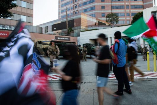 15일(현지시간) 불법 이민 강력 단속에 발하는 시위대가 해병대 앞을 지나가고 있다. (사진=AFP)