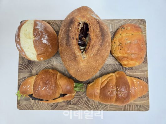 도마 위에 담긴 ETF 베이커리 빵 5종. 왼쪽 위부터 시계방향으로 쌀크림빵, 대추 무화과 깜빠뉴, 마늘버터 소금빵, 소금빵, 부추 명란 소금빵. (사진=한전진 기자)