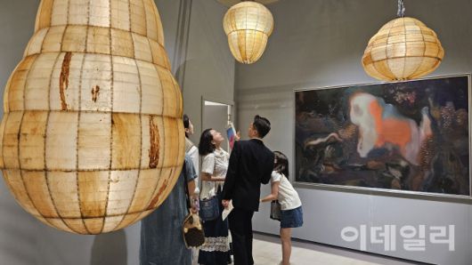 ‘프리즈 서울 2025’ 전경. 가족으로 보이는 관람객이 글래드스톤 부스에 걸리고 매달린 아니카 리의 조각·회화작품들을 둘러보며 즐거워하고 있다(사진=오현주 문화전문기자).