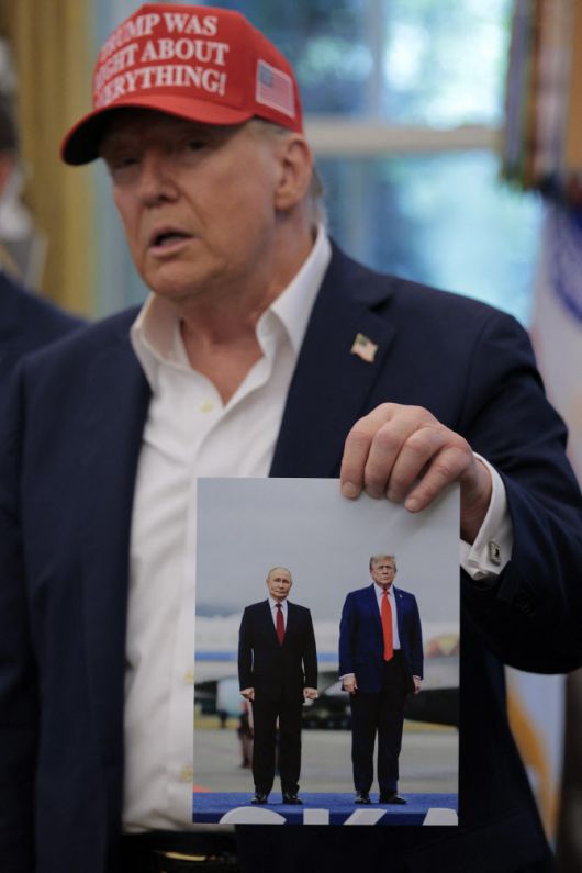 도널드 트럼프 미국 대통령이 올해 8월 22일 백악관 집무실에서 블라디미르 푸틴 러시아 대통령이 선물로 준 초상 사진을 들고 있는 모습.  (사진=AFP)