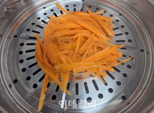 면 대신 사용할 당근을 일정한 굵기로 채 썬 뒤 찜기에 약 5분간 익힌 모습. 적당히 찌면 쫄깃한 식감이 살아난다. (사진=한전진 기자)