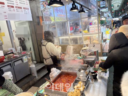 21일 서울 마포구 망원시장. 한 분식점 상인이 혹한에 어묵꼬치가 얼지 않도록 온열기 앞에서 꼬치를 데우며 장사를 준비하고 있다.(사진=석지헌 기자)