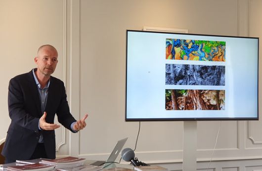 미술사학자 부터 판데르빈 박사가 그림 '나무뿌리들'(스크린 윗쪽), 엽서 속 사진(스크린 중간), 현재의 모습(스크린 아래쪽) 사이의 유사점을 설명하고 있다/오베르쉬르우아즈=손진석 특파원